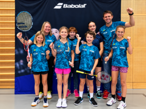 Badminton-Team feiert vor Babolat-Banner