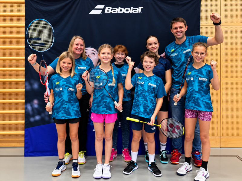 Badminton-Team feiert vor Babolat-Banner
